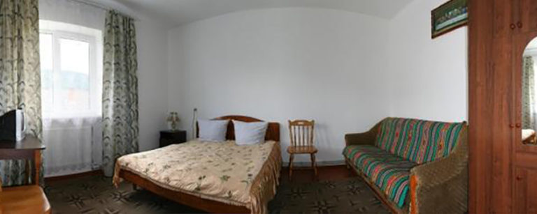 Cozy bedroom with a bed, sofa and a bright large window