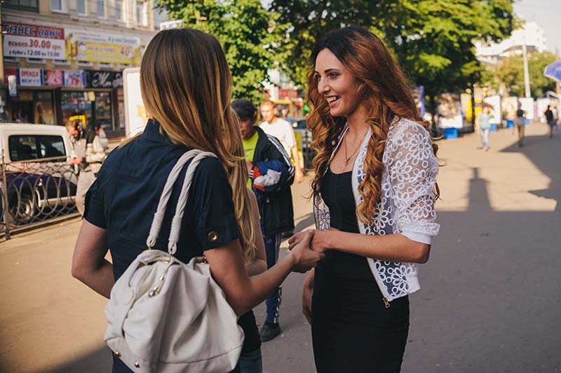 Two girl friends meet on a street.