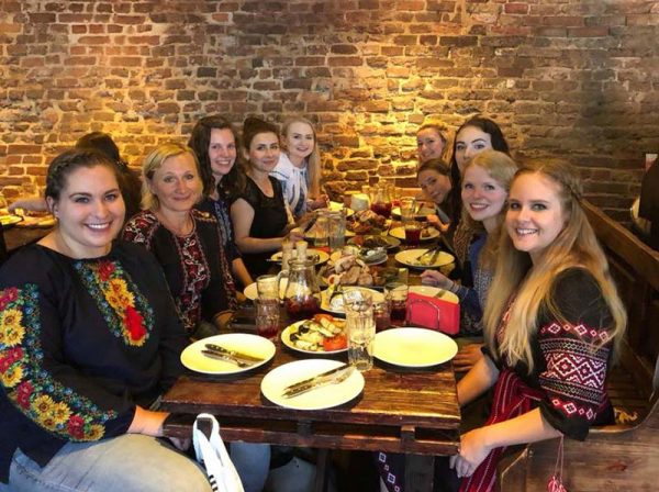 A group of young women in Ukrainian embroidered shirts are having a meal in a restaurant
