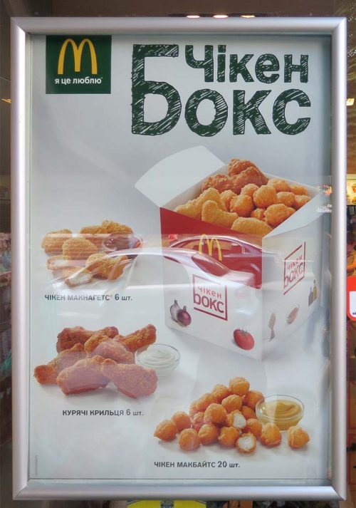 An advertisement of McDonalds chicken menu on a window of the restaurant.