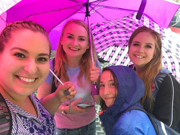 A group of young women standing with umrellas on a street